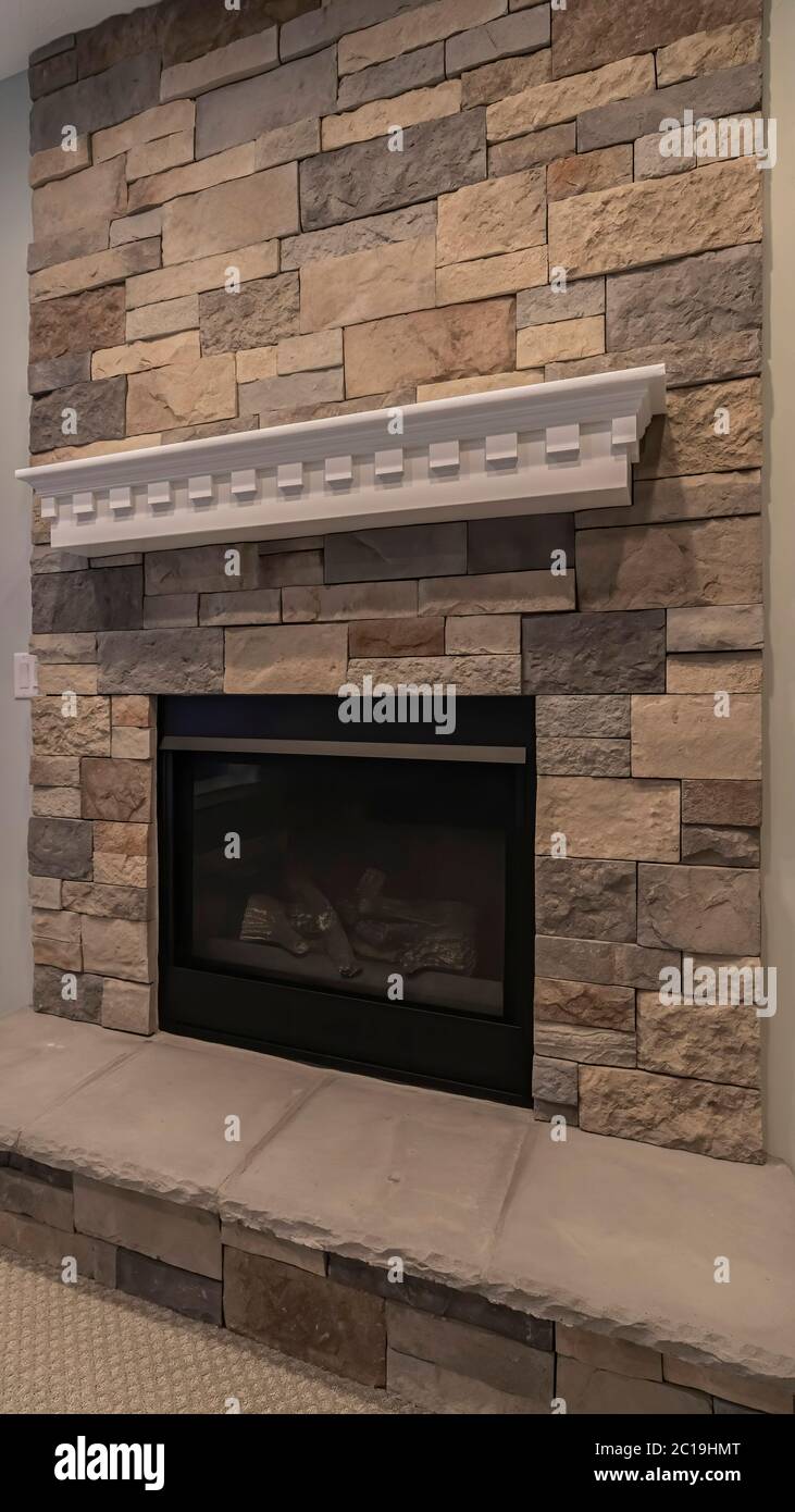 Vertical Modern fireplace and decorative shelf against stone brick accent wall of home Stock