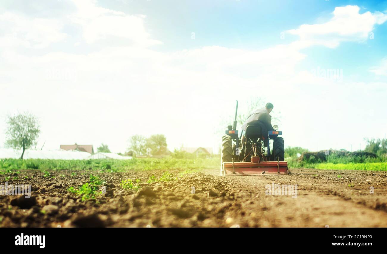 Farmer on a tractor with milling machine loosens, grinds and mixes soil. Loosening the surface, cultivating the land for further planting. Farming and Stock Photo