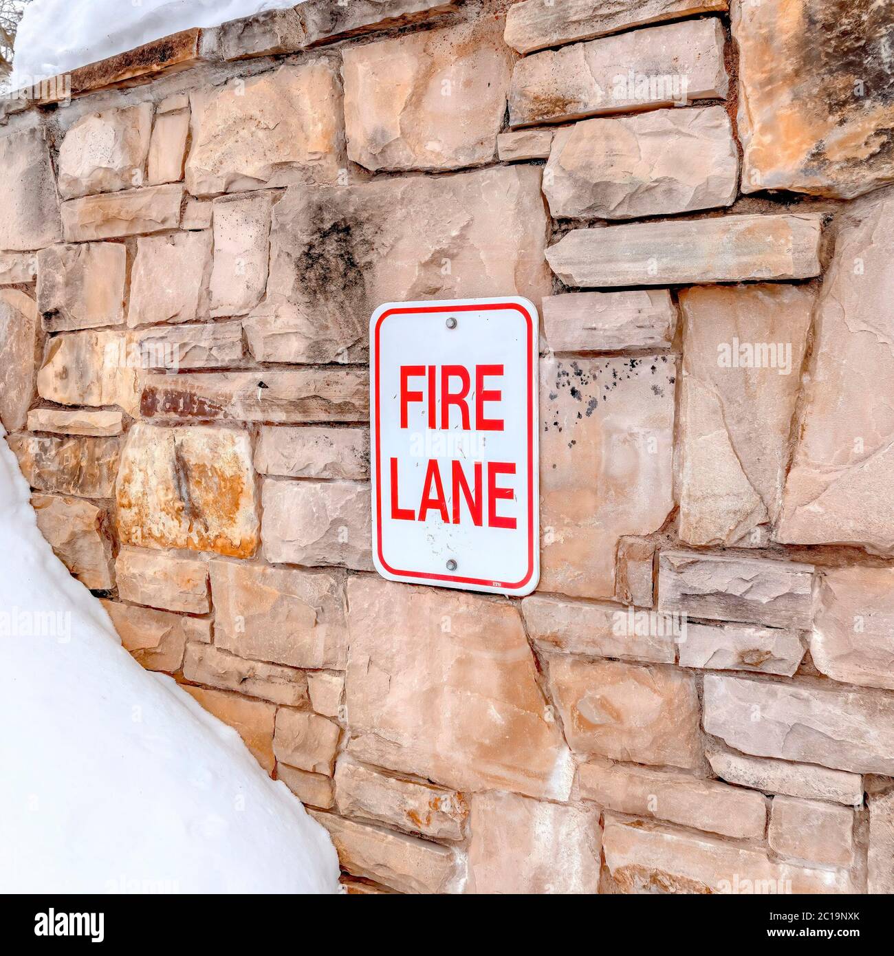Square Fire Line Square Fire Lane sign on stone retaining wall amid thick fresh snow on ...