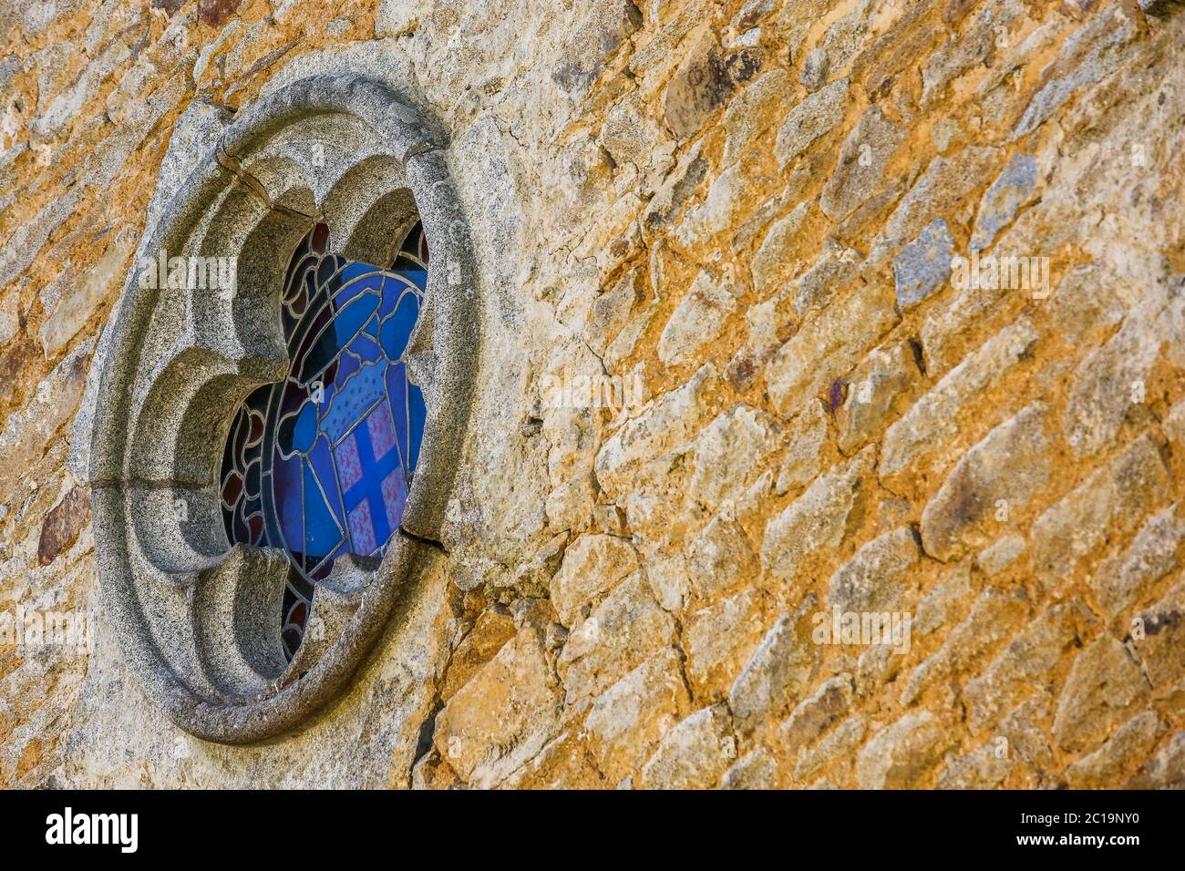 Small church window on a stone wall Stock Photo