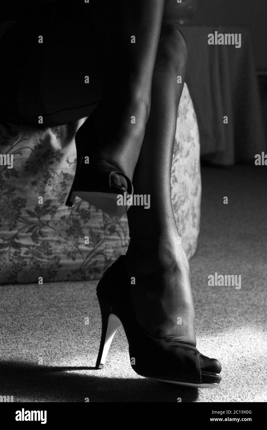 Legs covered from a pair of black seamed stockings and black stiletto heels Stock Photo