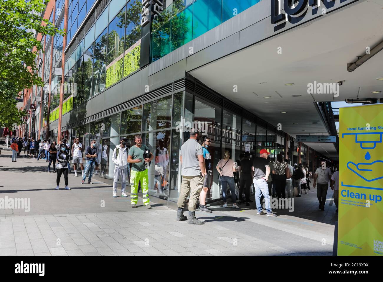 Wembley Park, London, UK. 15th June 2020. Shoppers queue outside the Nike  Store in the London Designer Outlet using the socially distanced 2 metre  markings. Coronavirus Covid-19 lockdown restrictions allow non essential