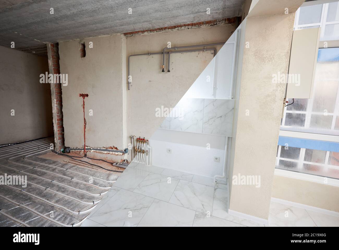 View from glazed loggia on big spacious new room in apartment before and after repairs. Empty walls, modern plastering, wallpapers, spotlight chandelier, floor heating pipe system, white shiny tiles Stock Photo