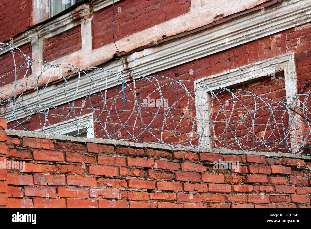barbed wire on the old red brick wall near the protected enterprise ...