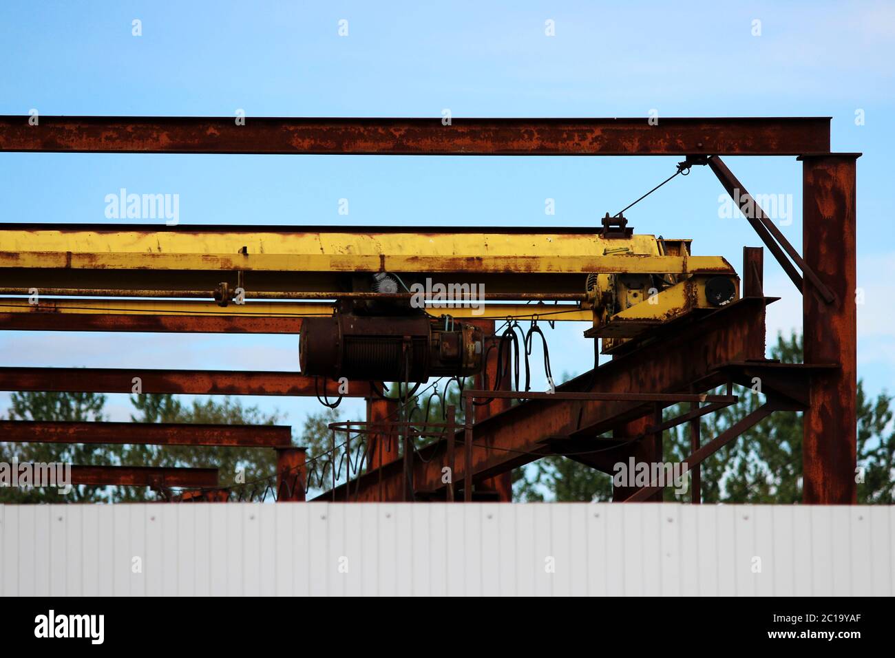 old rusty crane beam in the warehouse under the open sky near the building supermarket for handling operations. Stock Photo