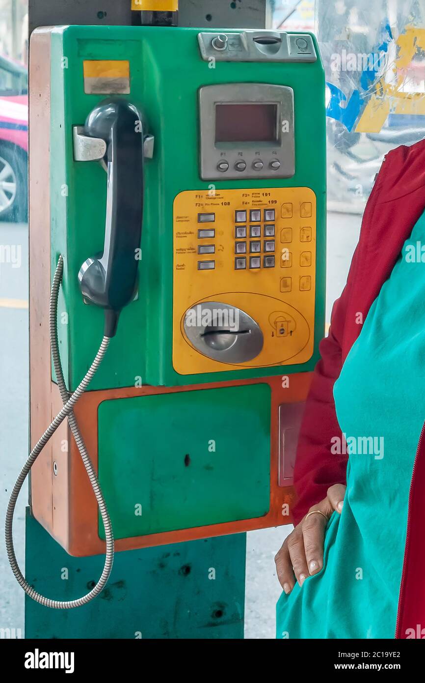 An old public telephone with keypad in a booth in central Bangkok, Thailand Stock Photo
