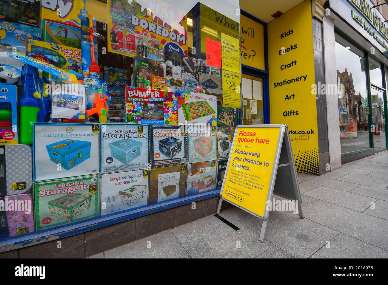 Exeter, Devon, UK.  15th June 2020.   Shops selling unessential items allowed to reopen today as coronavirus lockdown is eased further.  The Works store in the High Street at Exeter in Devon with a sign outside reminding customers of social distancing.  Picture Credit: Graham Hunt/Alamy Live News Stock Photo