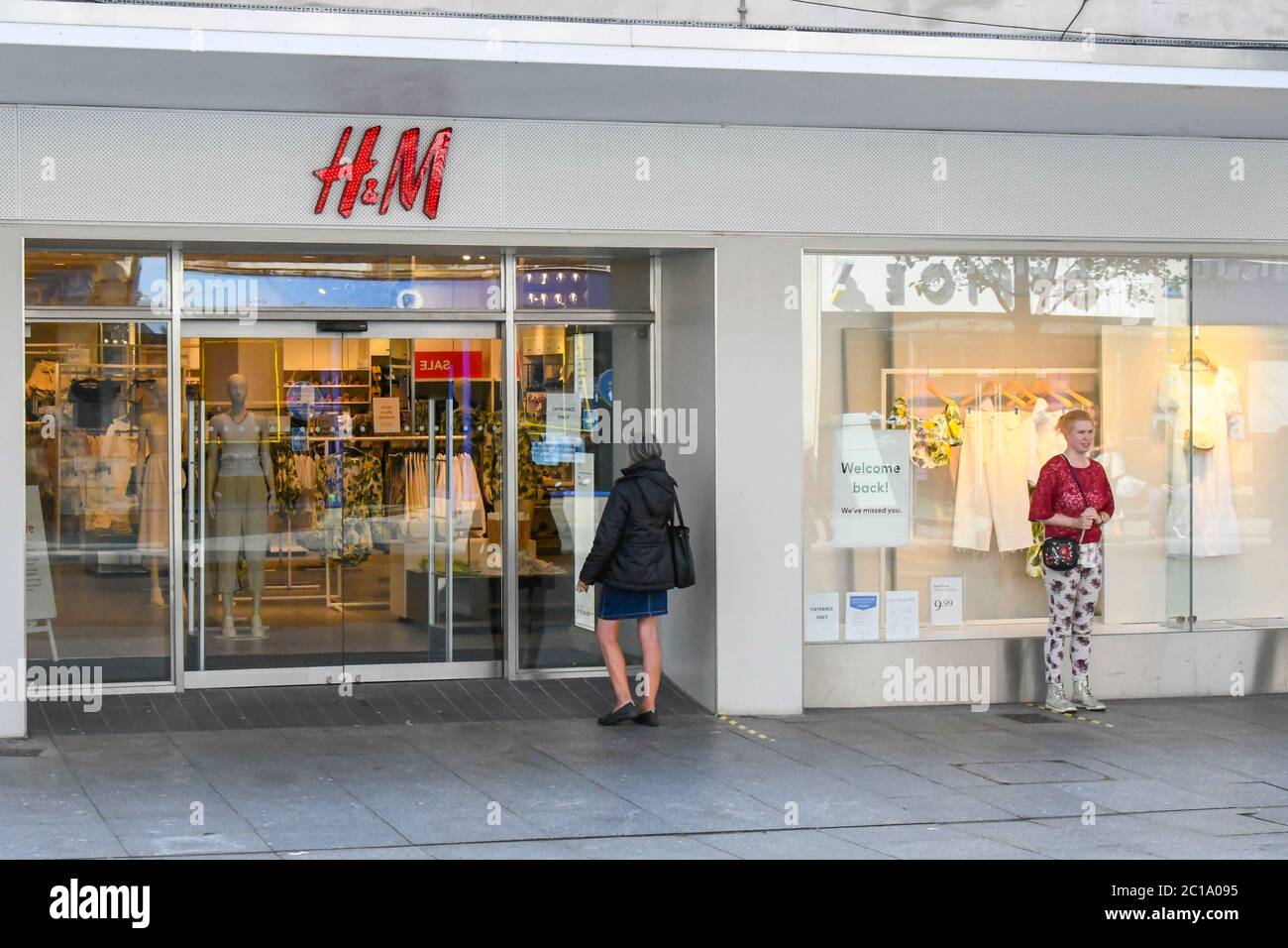 Exeter, Devon, UK. 15th June 2020. Shops selling unessential items allowed  to reopen today as coronavirus lockdown is eased further. Customers queuing  outside the H&M store in the High Street at Exeter