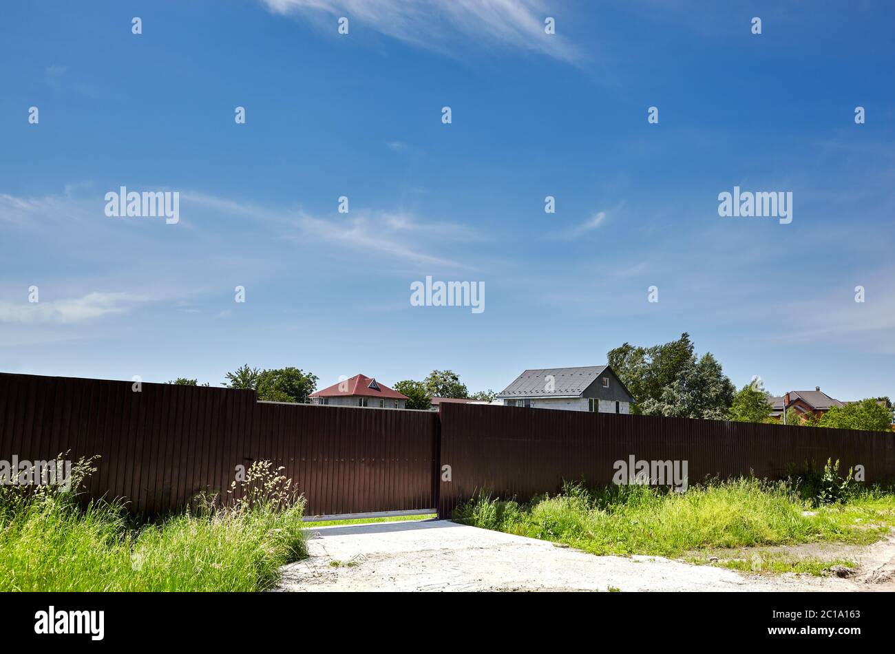 Metal fence of a house in suburb neighborhood. Rural landscape with sky ...