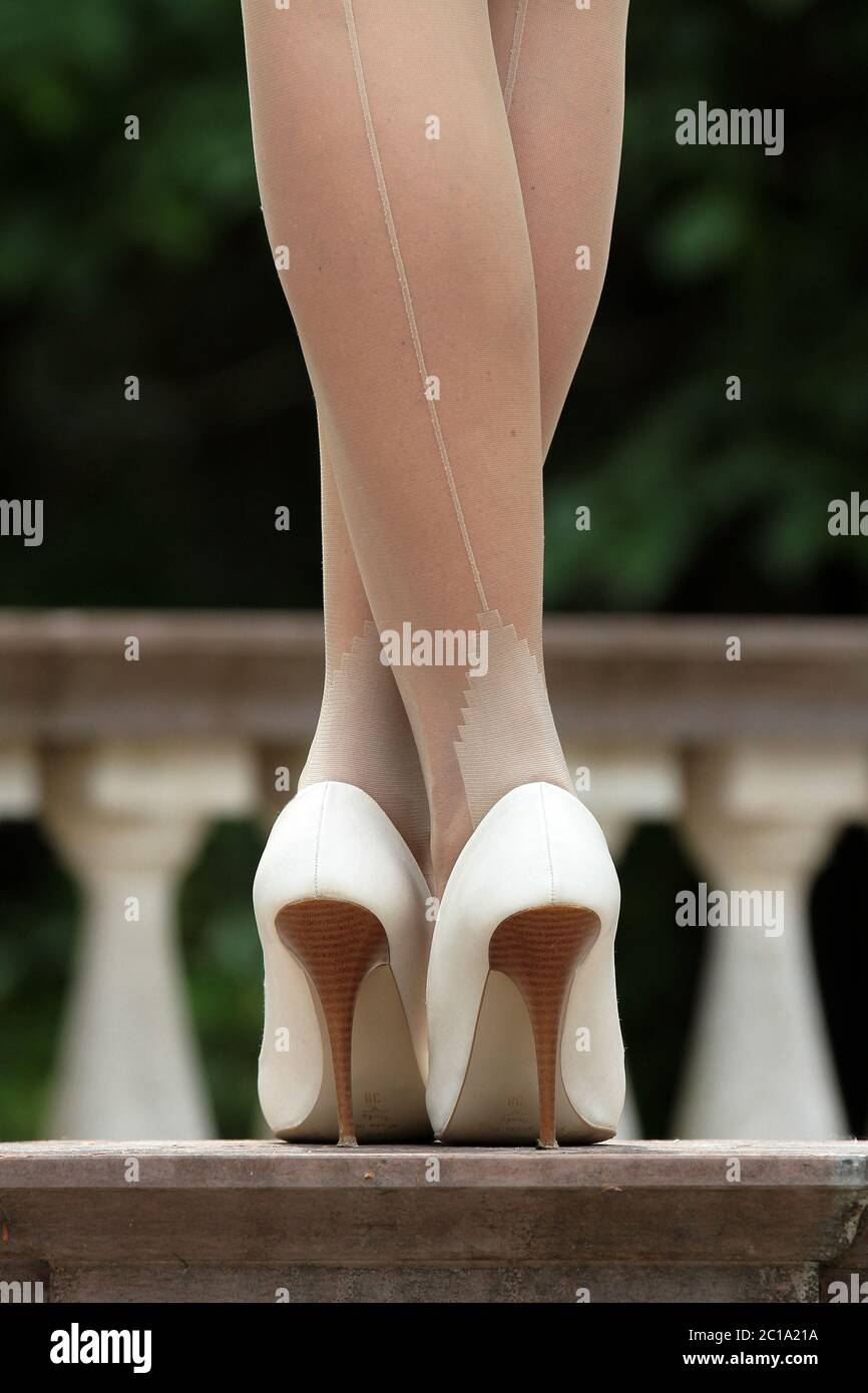 Legs covered from a pair of seamed cream color pantuhose and white stiletto heels Stock Photo