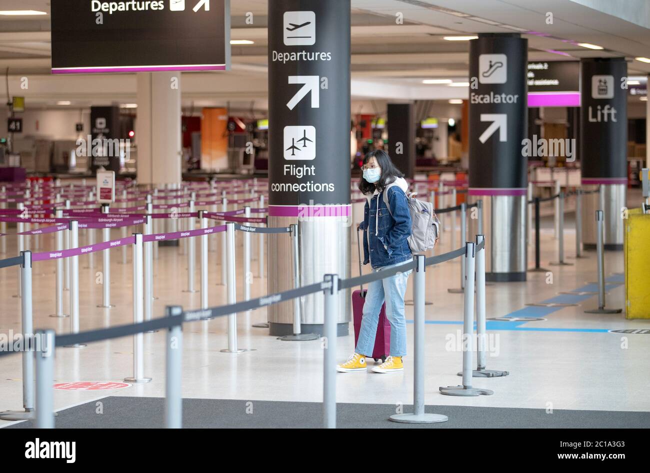 A passenger, wearing a protective face mask, waits at the check-in area at Edinburgh Airport. Stock Photo
