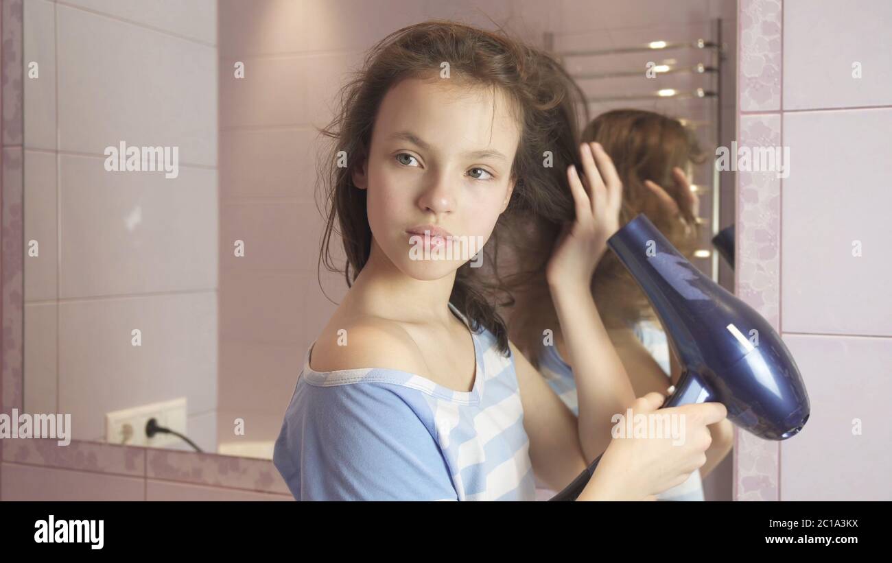 Beautiful teen girl dries hair a hairdryer in bathroom Stock Photo - Alamy