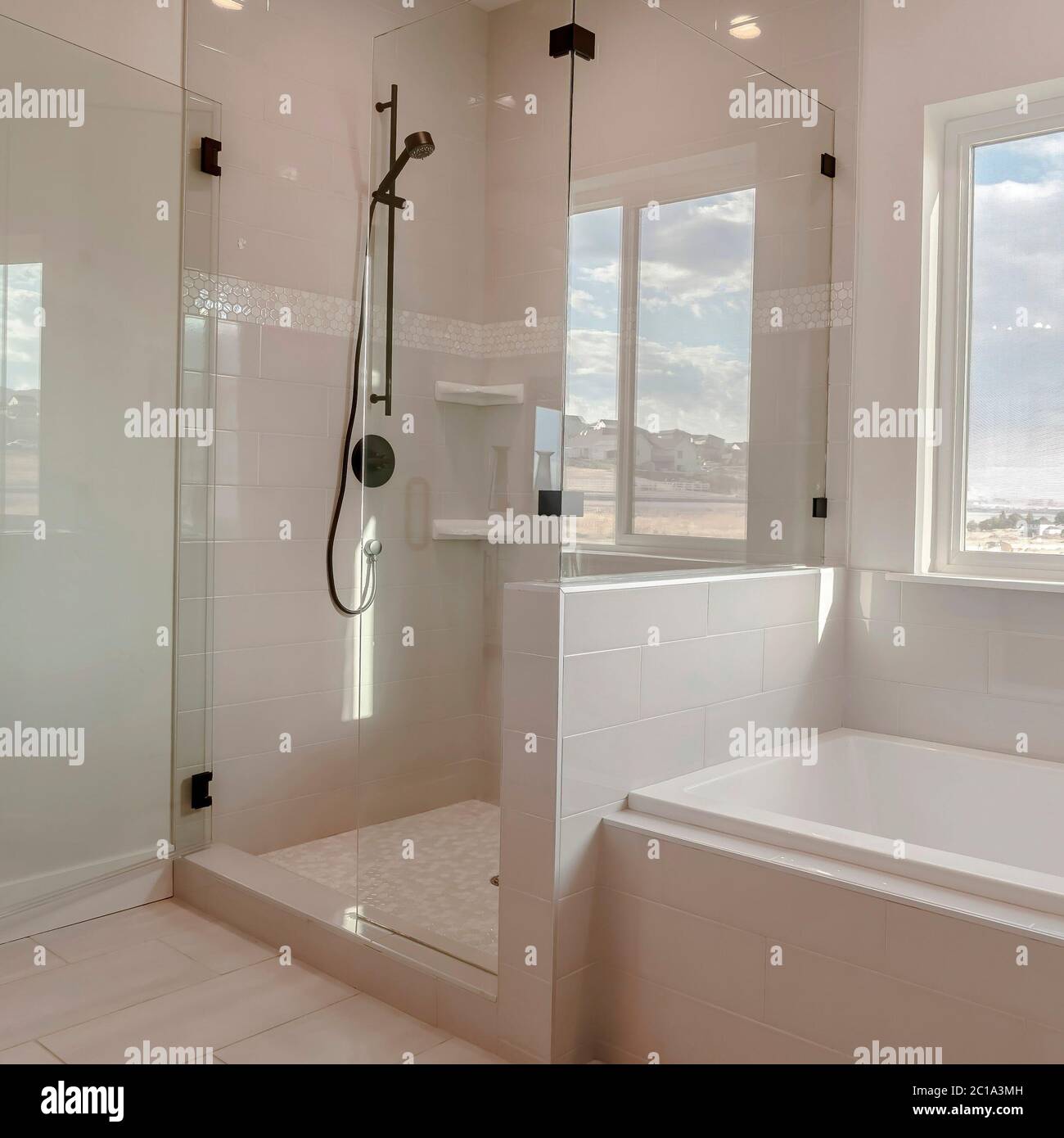 Square Built in bathtub with black faucet and shower stall with half glass enclosure Stock Photo