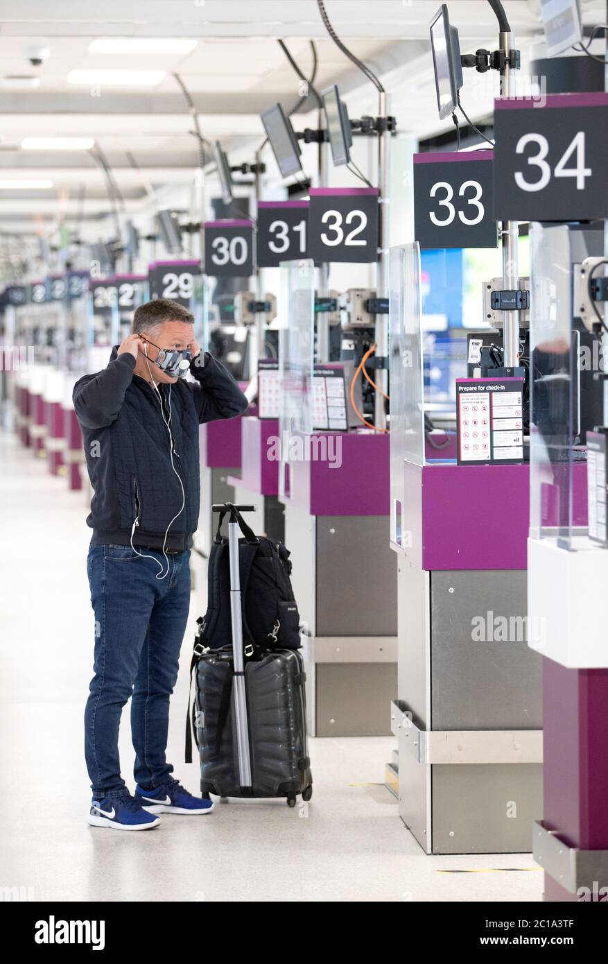 A passenger puts on a protective face mask in the check-in area at Edinburgh Airport. Stock Photo