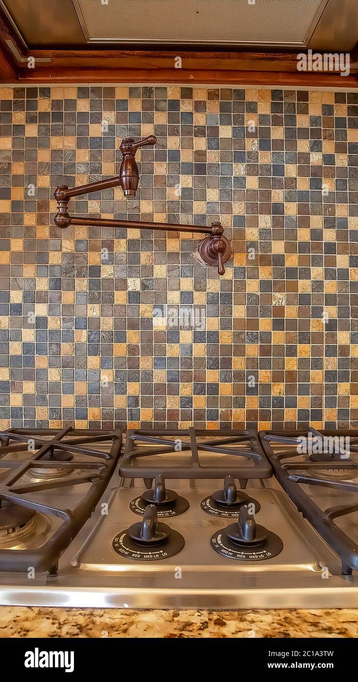Vertical frame Cooktop and exhaust hood inside kitchen with faucet on
