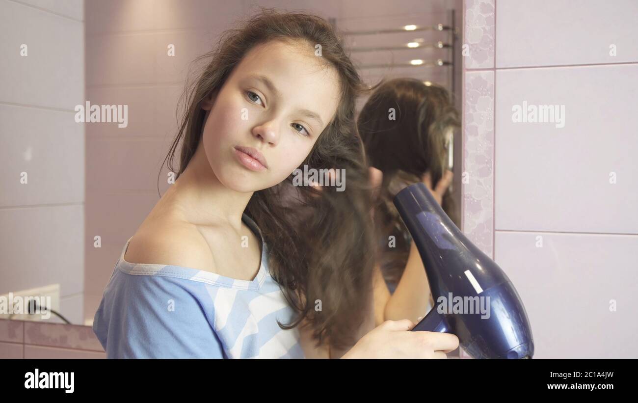 Beautiful teen girl dries hair a hairdryer in bathroom Stock Photo - Alamy