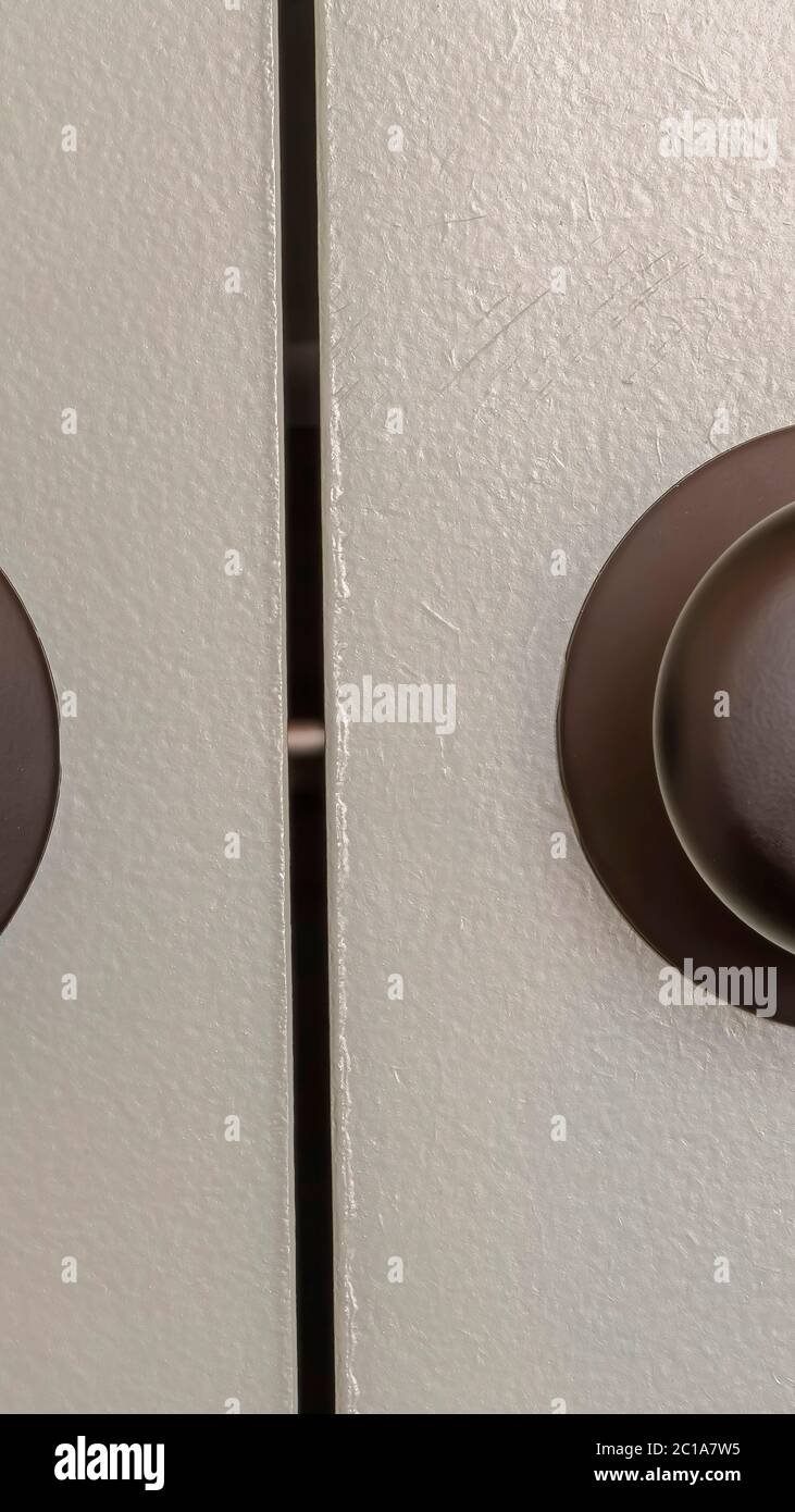 Vertical Close up view of matte black round door knobs of a gray