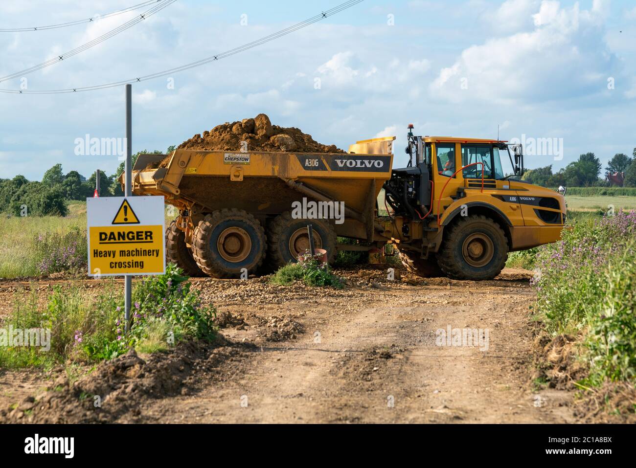 A fully loaded dump truck crosses a dirt path, which is used as a bridleway. To dump it 's load from phase one to phase two to build the mine walls. Stock Photo
