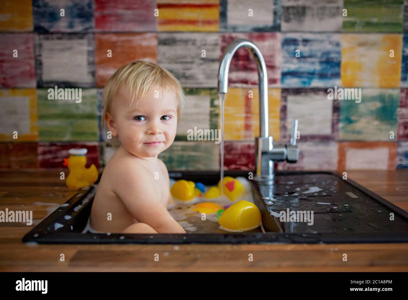 Cute Smiling Baby Taking Bath In Kitchen Sink Child Playing With Foam And Soap Bubbles In Sunny Kitchen With Rubber Ducks And Toys Little Boy Bathin Stock Photo Alamy