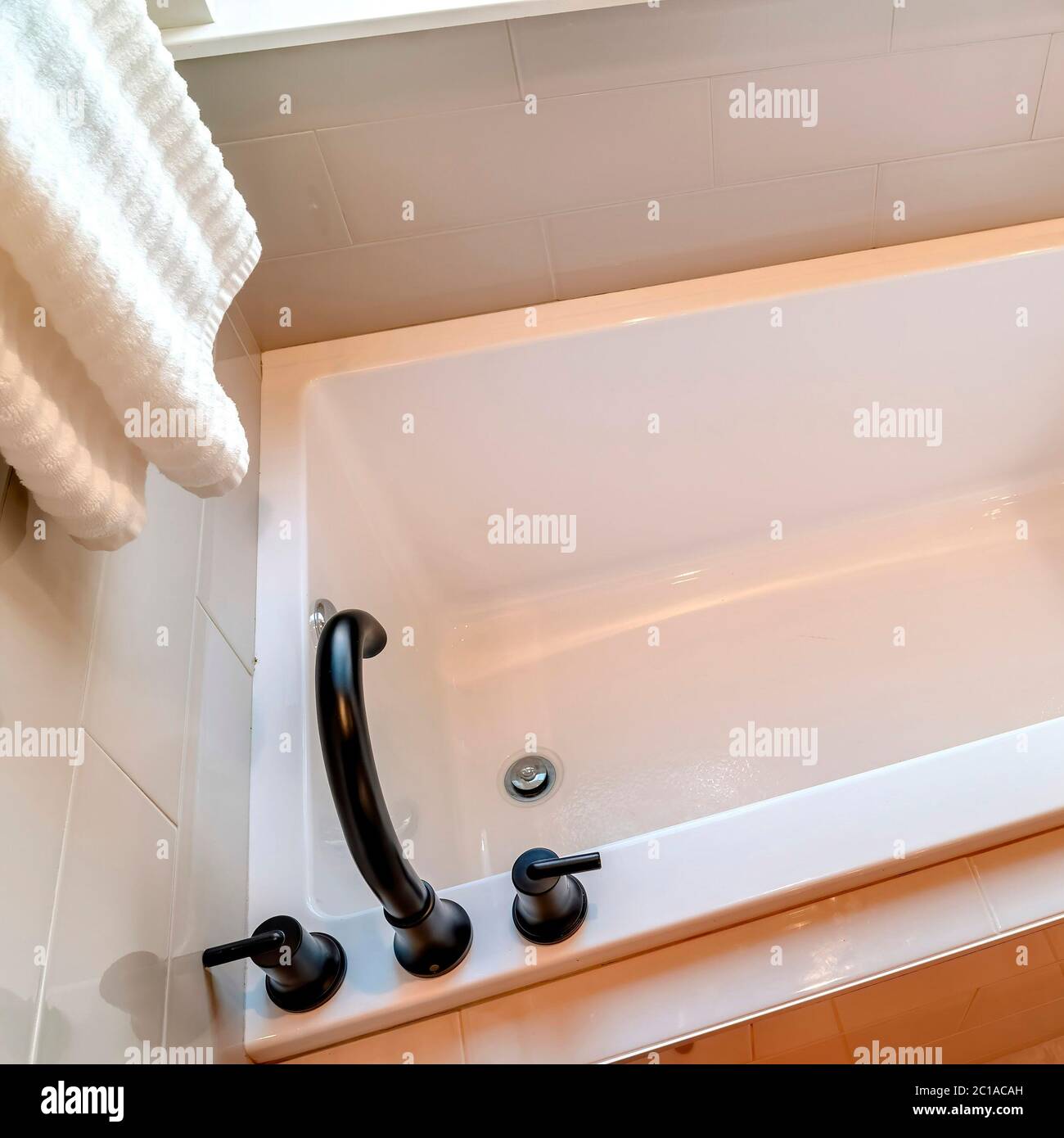 Square frame Rectangular bathtub with black faucet and handles against