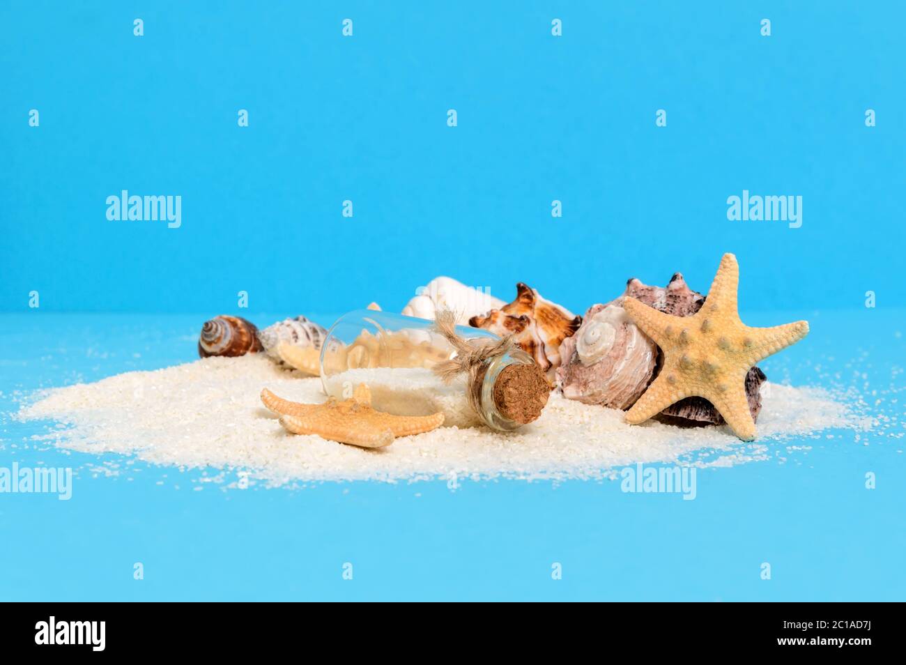 Small treasure island: desolate white sand shore with message bottle, sea stars or starfish and shells. Summer travel, adventure or exploration concep Stock Photo