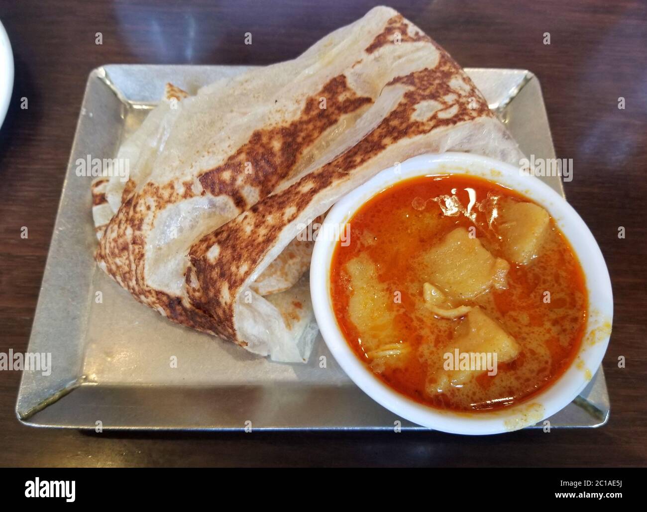 Malaysian pancake, also known as roti canai, with a side of curry gravy Stock Photo