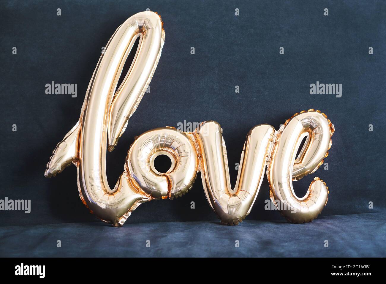 Shaped golden balloon of word Love on dark background Stock Photo