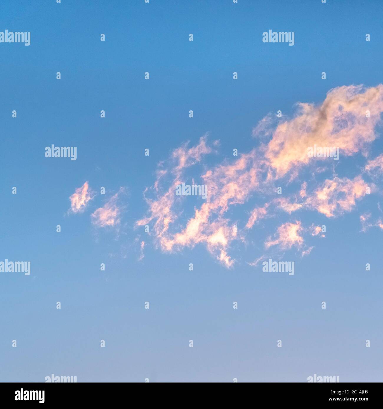 Square Wispy white clouds tinged pink at sunset Stock Photo
