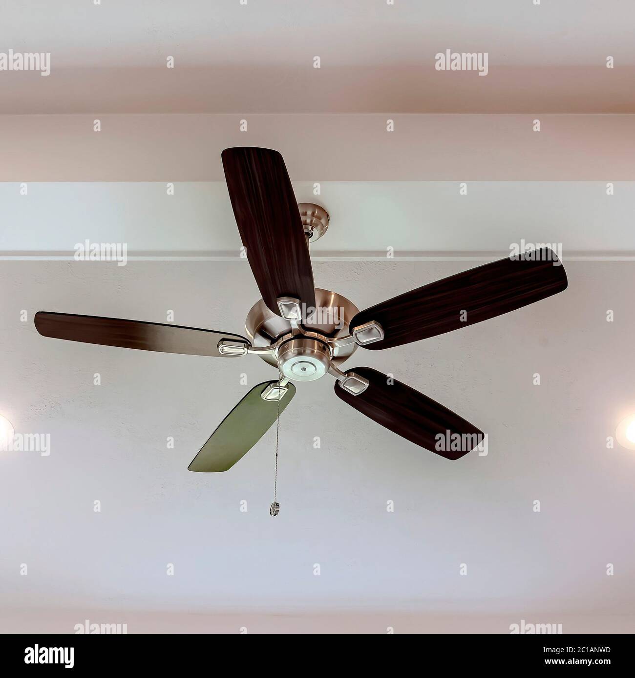 Square Ceiling fan with wood blades and built in lights on the ceiling beam of home Stock Photo