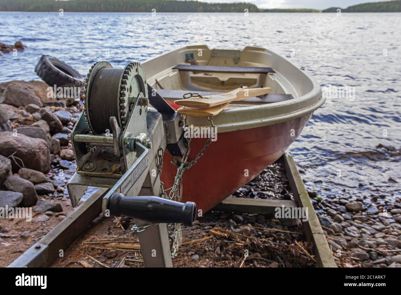 A red rowing boat (oar boat) on a slipway with a winch on lake shore in