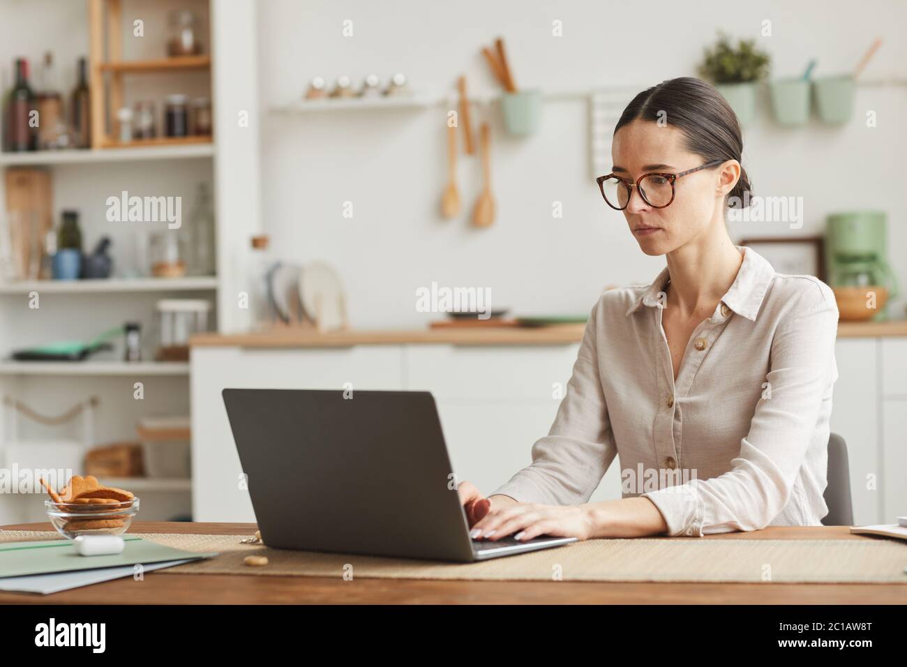Portrait of elegant businesswoman wearing glasses while using laptop at cozy home office workplace, copy space Stock Photo