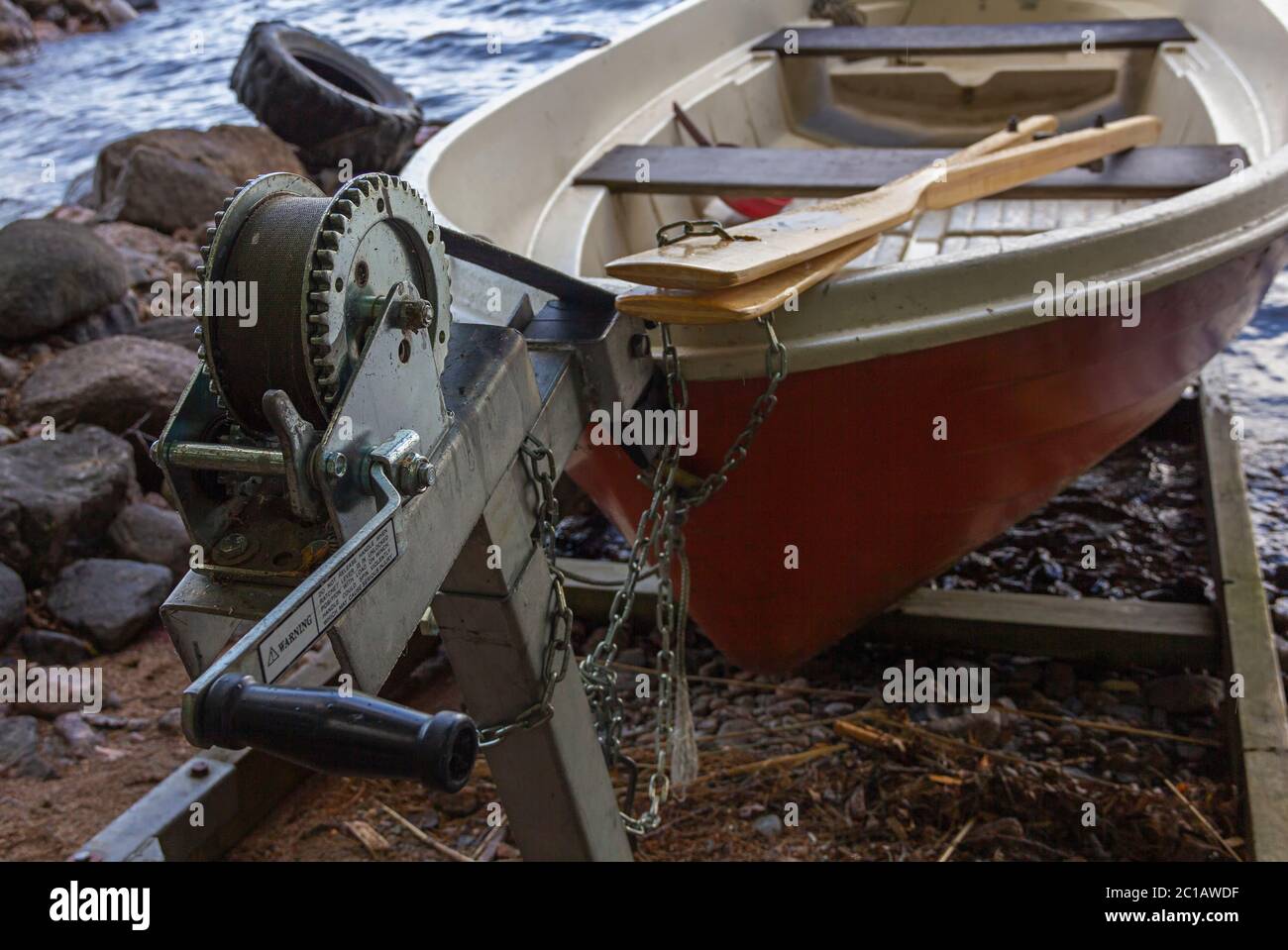 A red rowing boat (oar boat) on a slipway with a winch on lake shore in Finland Stock Photo