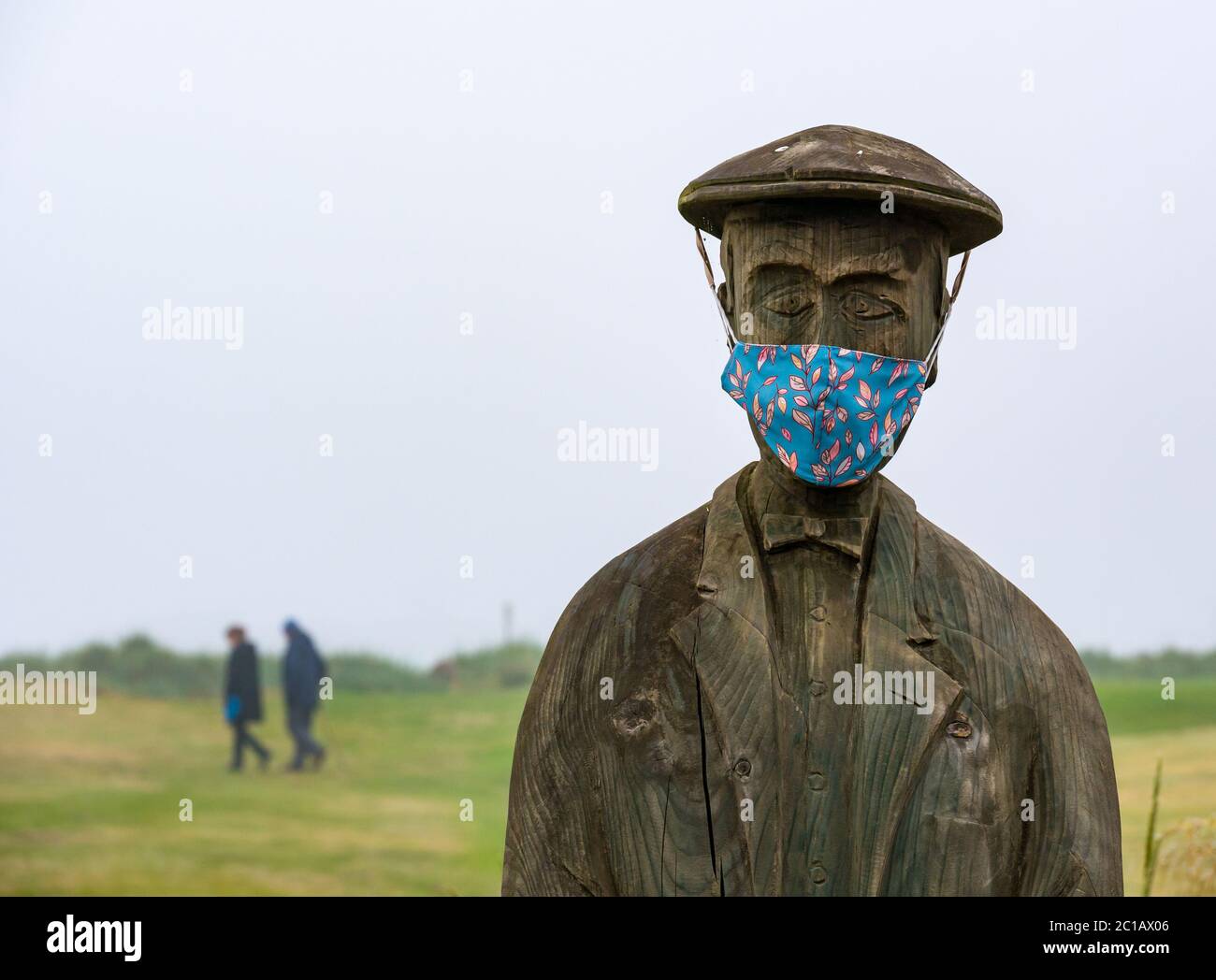 North Berwick, East Lothian, Scotland, United Kingdom, 15th June 2020. UK Weather: thick fog continues for the 3rd day in East Lothian with few people in the popular seaside town. A wooden statue of Ben Sayers, a 19th century professional golf player by Ed Robinson, has acquired a colourful face mask on Rotary Way on Elcho Green Stock Photo