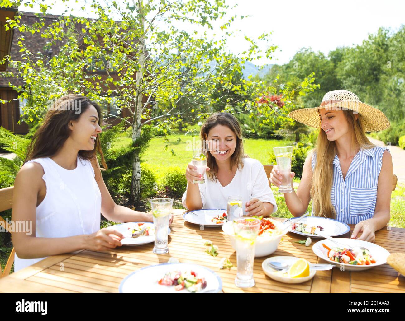 Happy female friends with glasses of lemonade at dining table Stock Photo