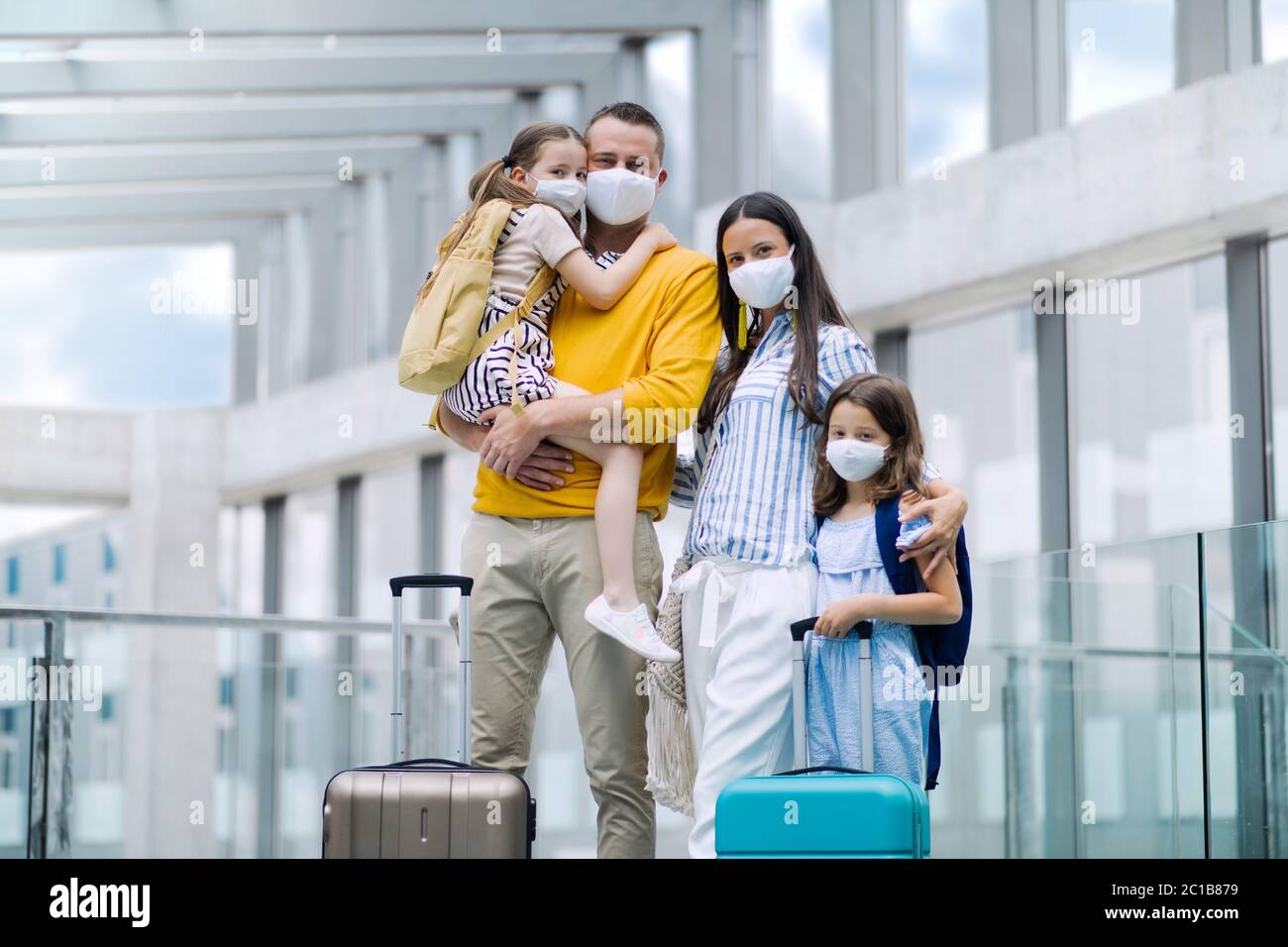 Family with two children going on holiday, wearing face masks at the