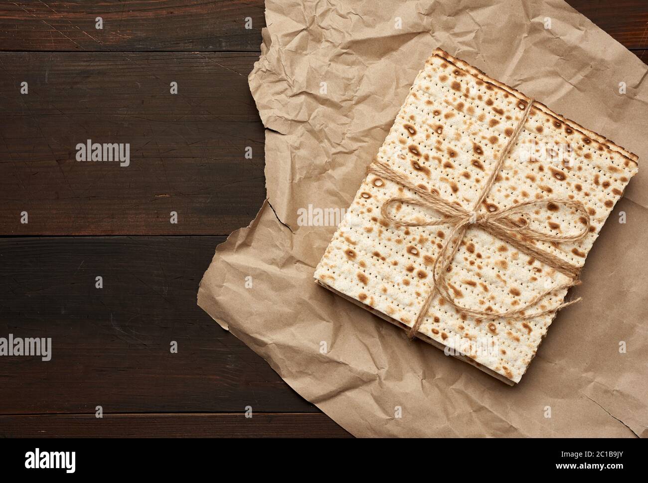 bandaged stack of baked square matzoh on brown paper, top view, copy space Stock Photo