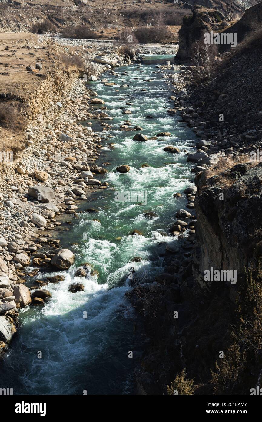Stormy mountain river with stones splashes and foam with clear drinking water of emerald color. The concept of natural sources o Stock Photo