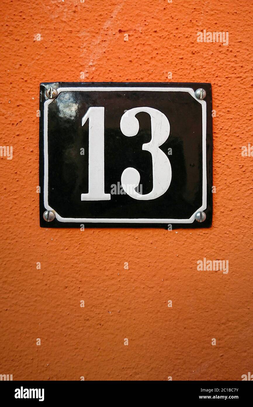the number thirteen on an orange wall Stock Photo