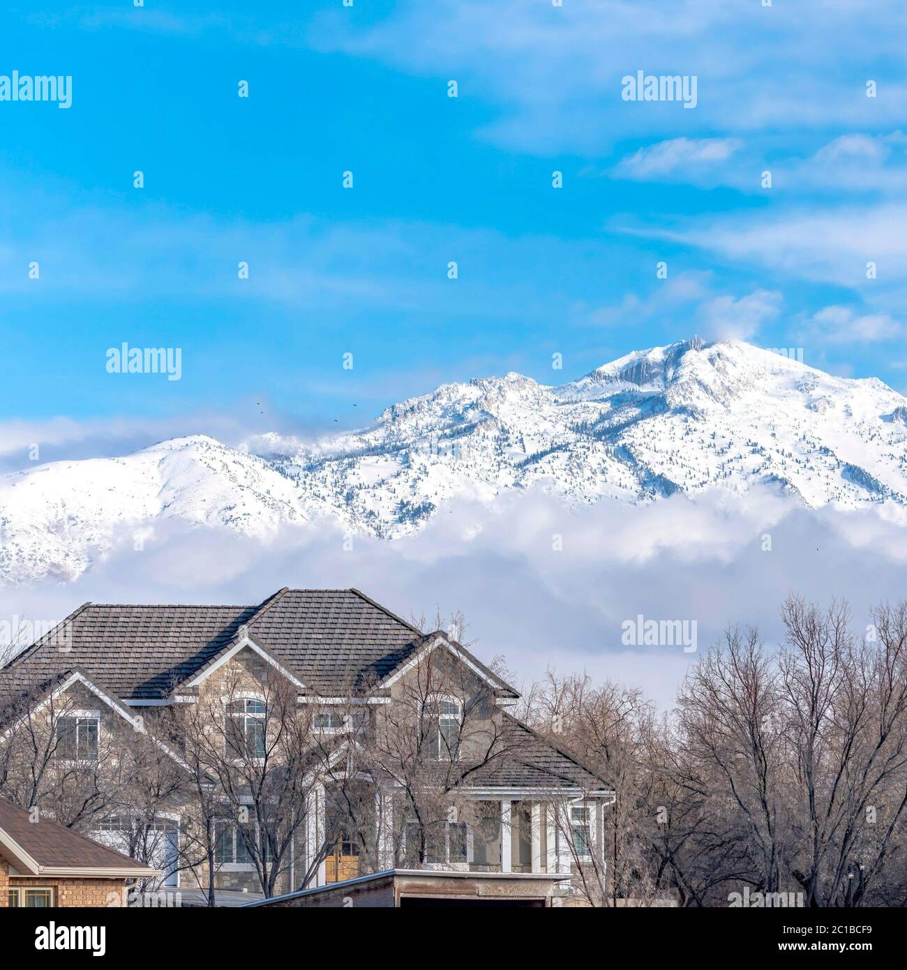 Square Peaks of a magnificent snowy mountain over low puffy clouds ...