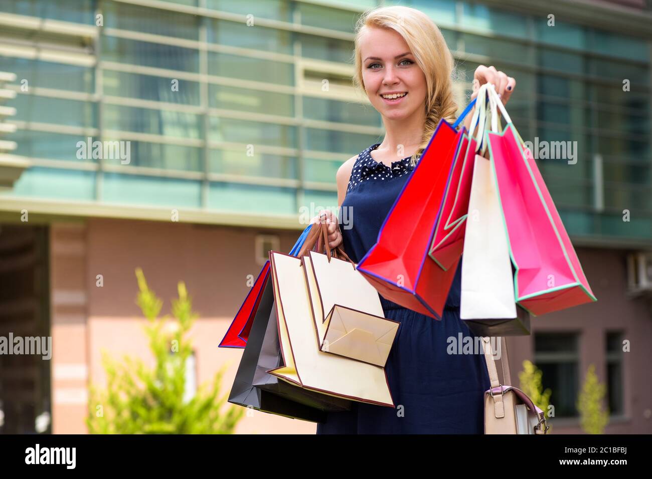 Elegant blonde woman with a shopping bag, spends money buying fashion  clothes in Singapore most luxury glamorous shopping complex on Orchard  Road. Caucasian lifestyle lady shopper in a mall. Photos
