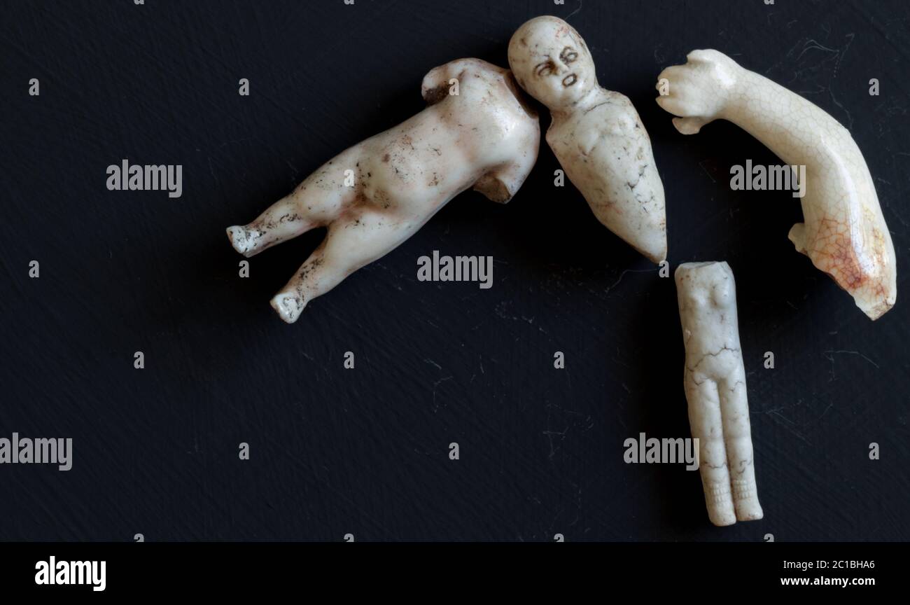 Creepy retro broken doll face and body parts isolated on grunge black background Stock Photo