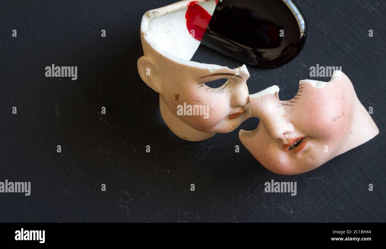 Broken doll faces and blood isolated on grunge black background with blood spatter. Conceptual image Stock Photo