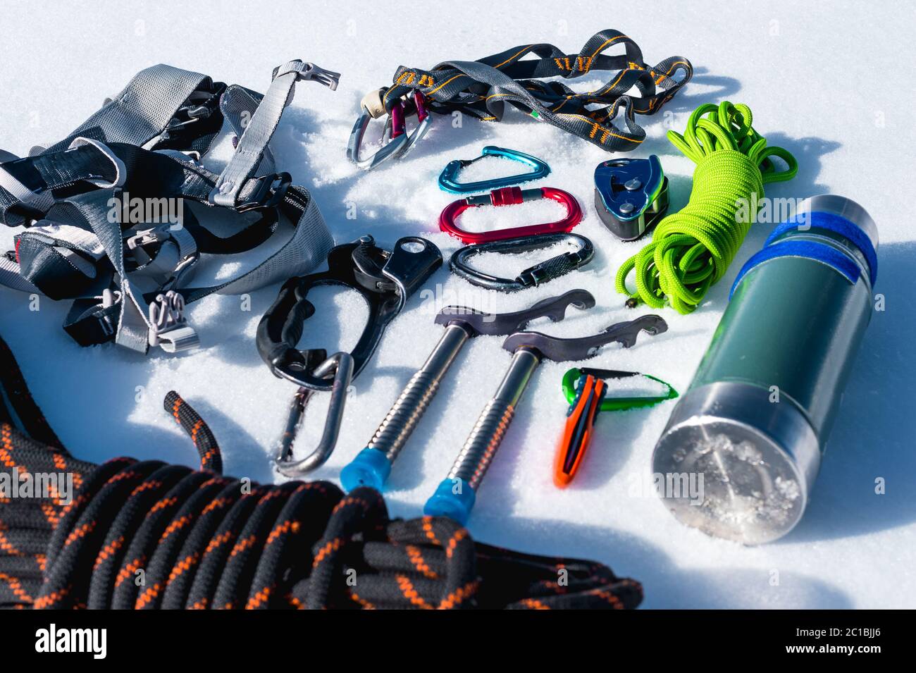 Close-up of winter climbing equipment on fresh snow on a sunny day. Carbines with a rope gazebo and zhumar as well as other adap Stock Photo