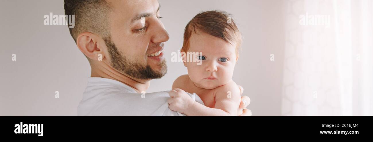 Caucasian father holding newborn baby. Man parent rocking child daughter son on hands. Authentic lifestyle candid moment. Young dad family life Stock Photo