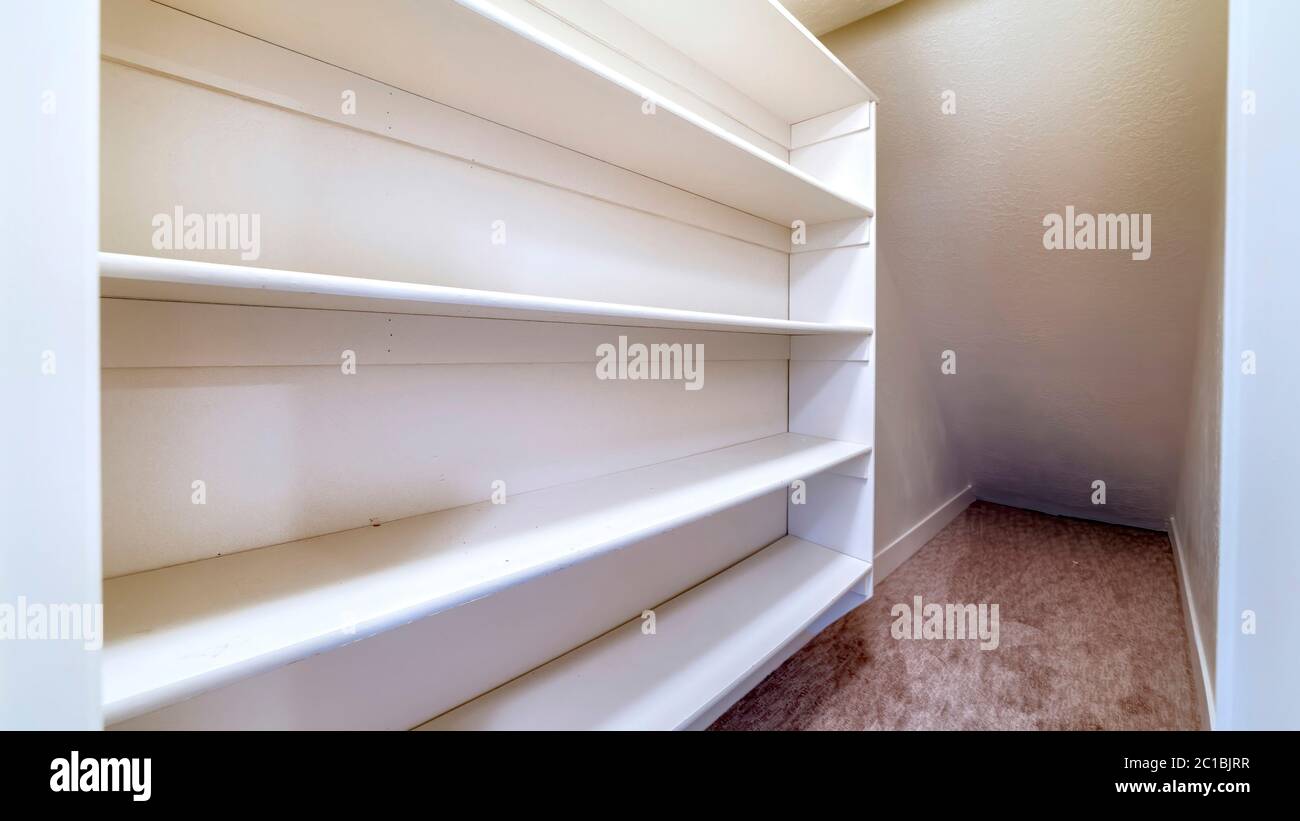 Panorama Small walk in closet with empty long cabinet shelves under ...