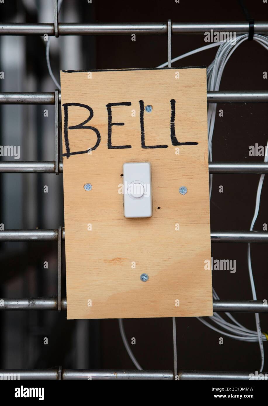 A white door bell on a piece of wood with screws with the word Bell Stock Photo
