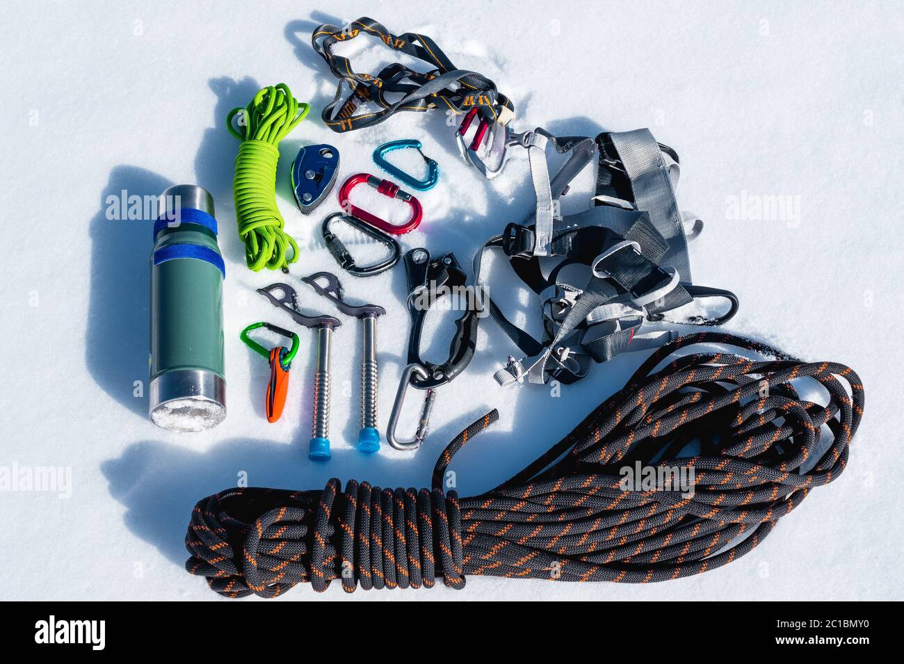 Close-up of winter climbing equipment on fresh snow on a sunny day. Carbines with a rope gazebo and zhumar as well as other adap Stock Photo