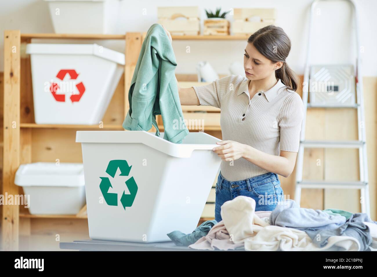Young woman recycling her wardrobe she throwing her clothes out into
