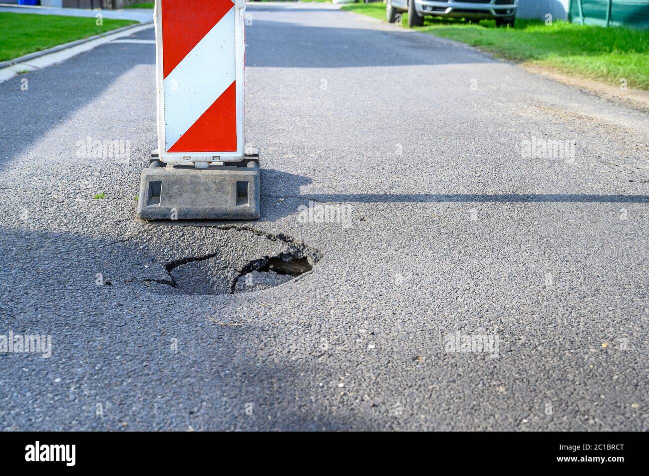 Pothole on asphalt street with detour alert traffic sign Stock Photo