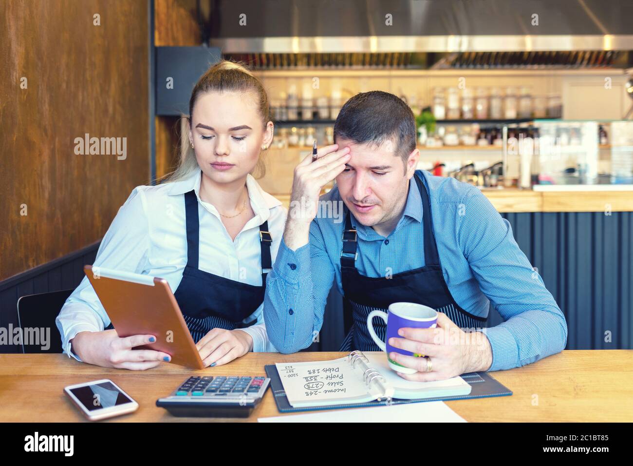 Mature new small business owners calculating online restaurant bill expenses and taxes Stock Photo
